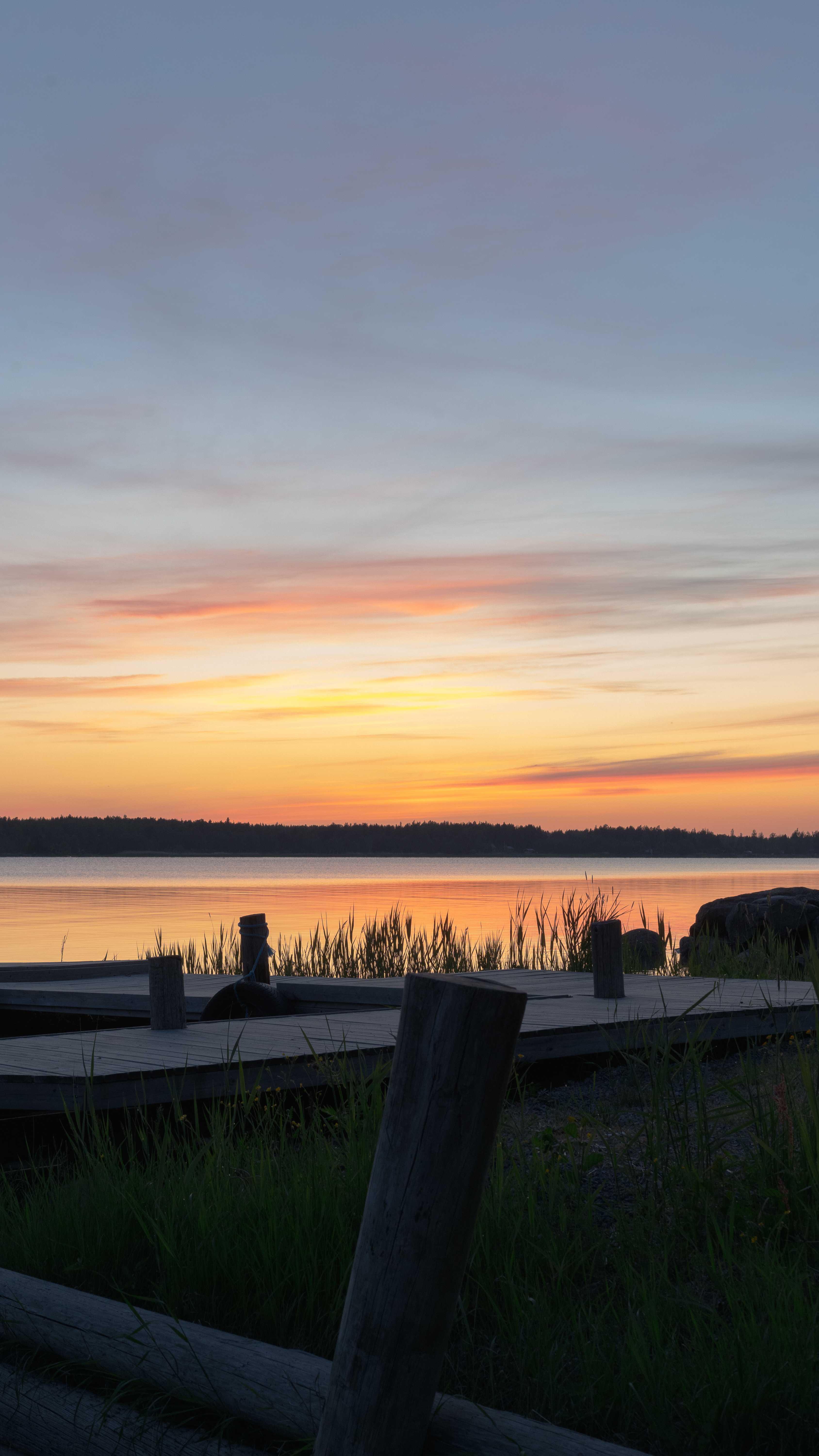 Vibrant sunset over a calm lake with wooden dock